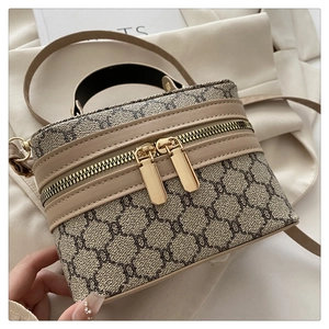 Close-up of vintage patterned box bag with brown leather trim and golden zippers