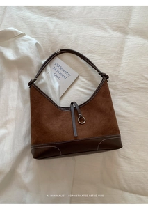 Detail view of brown suede shoulder bag with contrast stitching and silver metal buckle