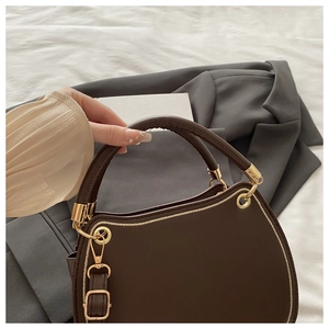 Close-up of a dark brown leather saddle bag with golden hardware and stitching details