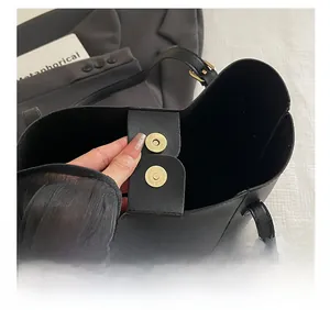 Detail of magnetic buckle closure and embossed logo on black leather tote bag