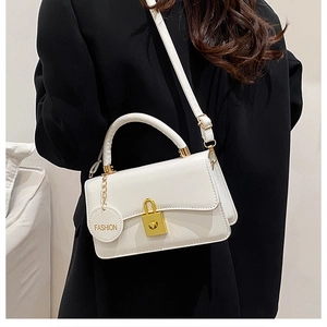 Detail der weißen PU-Ledertasche mit goldenem Schloss und Mode-Anhänger
