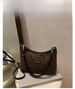 Detail of leopard print canvas tote bag with leather logo tag and thin shoulder strap