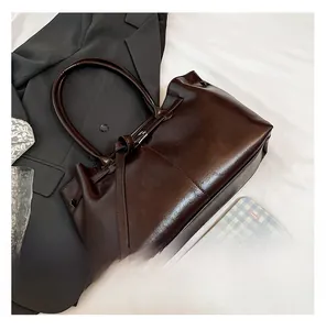 Detail view of glossy brown vintage tote bag with decorative knot and leather texture