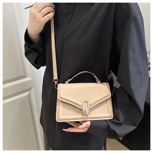 Close-up of cream square handbag with gold oval metal clasp and smooth PU leather finish
