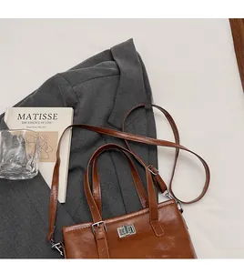 Detail view of brown vintage leather tote with silver metal clasp and long shoulder strap