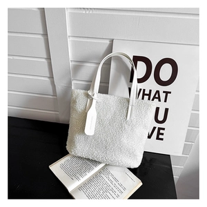 Detail of white plush tote bag with faux leather handles on a minimalist wooden background