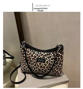 Detailed view of leopard print shoulder bag with black leather trim and metal logo plate