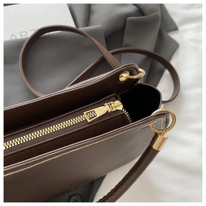 Detailed macro view of dark brown handbag zipper and golden metal hardware texture
