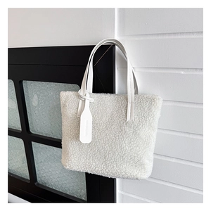 Close-up of white plush lamb wool tote bag featuring synthetic leather handles and tag