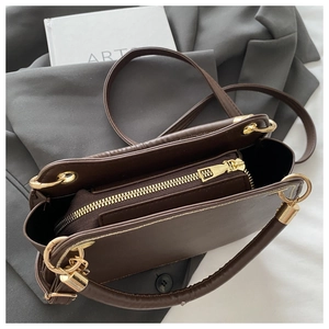 Detail of dark brown leather handbag interior with gold zipper pocket and fine stitching