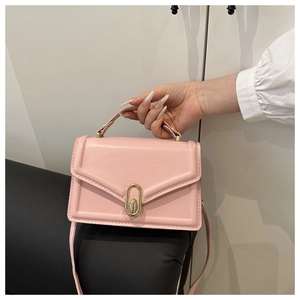 Detail of pink small square bag featuring matte leather and gold oval twist lock