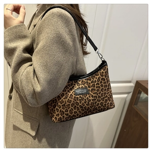 Detail view of leopard print underarm bag with black trim and metallic buckle accents
