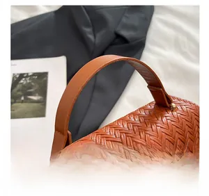 Detailaufnahme der braunen gewebten Handtasche mit hochwertiger Metallschnalle und Griff