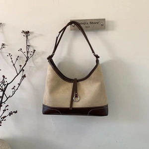 Elegant canvas and brown leather tote bag with metallic ring and minimalist design