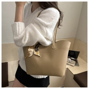 Chic beige tote bag with decorative silk scarf accessory shown in a workspace setting