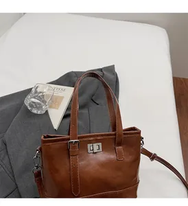 Detailed view of the brown textured leather surface and silver metal twist lock on tote bag