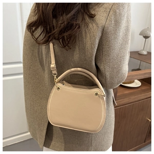 Detail of apricot crossbody bag showing thick handle and polished gold metal hardware