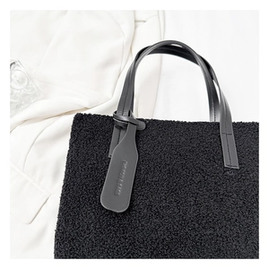 Close-up of black fuzzy lamb wool tote bag featuring a leather strap and fashion tag