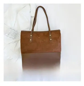 Détail du cabas en daim marron avec nœud doré métallique et finitions en cuir