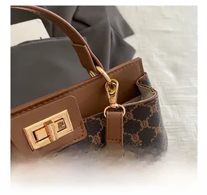 Gros plan des détails dorés et du motif Triomphe sur un sac à bandoulière marron