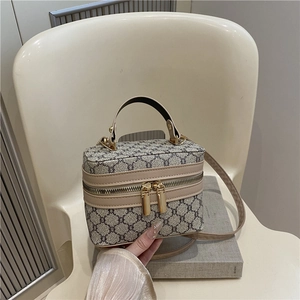Retro monogram box crossbody bag with gold zippers and adjustable shoulder strap on a chair