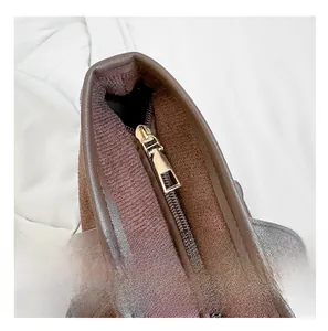 Détail de la fermeture éclair dorée sur un sac à bandoulière en suédine marron