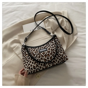 Detail of leopard print underarm bag resting on a cream blazer and an art book