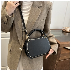 Detail of a black leather handbag with gold trim and adjustable shoulder strap
