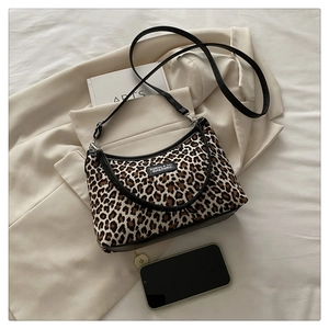 Detail of leopard print crossbody bag with black leather trim on minimalist background