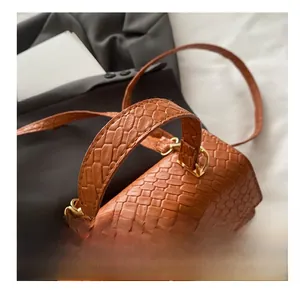 Détail d'un sac à main orange en cuir tressé avec fermoir doré et texture raffinée