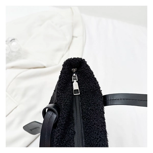 Detail of plush black bucket bag featuring premium faux fur texture and silver zipper finish