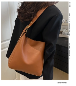Detail view of large brown caramel bucket bag with wide shoulder strap and gold hardware
