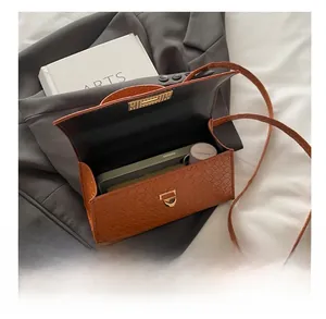 Vue intérieure du sac bandoulière marron montrant l'espace pour téléphone et maquillage