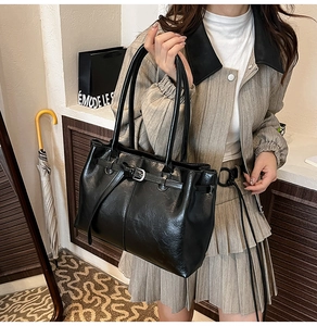 Détail du sac cabas en cuir noir avec boucles en métal argenté et lanières élégantes