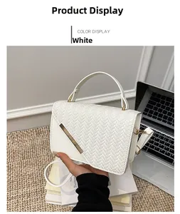 Detail of white leather handbag featuring woven flap texture and gold metal bar accent