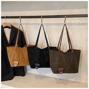 Detailed display of large suede tote bags in caramel, black, and coffee on a metal rack