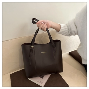 Detail of dark brown leather tote bag with gold lettering and adjustable shoulder strap