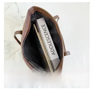 Vue de dessus du grand sac cabas marron contenant des livres et une tablette