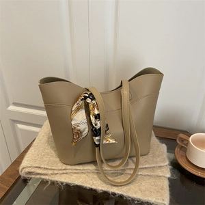 Elegant khaki faux leather tote bag with decorative printed scarf on knitting blanket