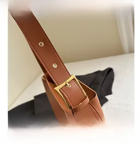 Detail of adjustable caramel faux leather strap with golden square buckle and eyelets