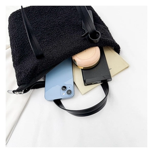 Internal view of the black shearling tote bag showing daily storage capacity for gadgets