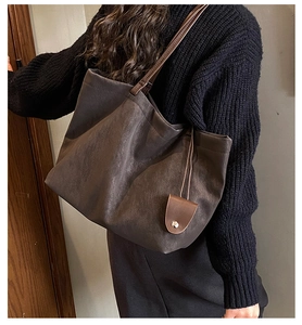 Detail of dark brown tote bag with suede texture and small pouch on shoulder