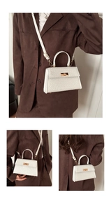 Détail du mini sac blanc texturé avec fermoir rotatif doré et poignée supérieure fixe