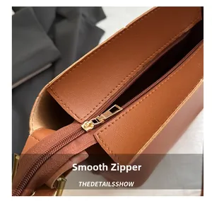 Close-up of smooth golden metal zipper detail on brown leather bucket bag