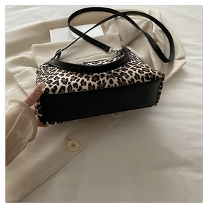 Detail view of leopard print tote bag with black leather trim and adjustable shoulder strap