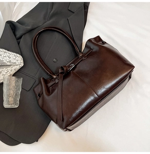 Detail of dark brown leather tote bag with elegant buckle and tie-front strap detail