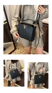Détail du sac à main en cuir grainé noir avec boucle dorée en V et poignée supérieure