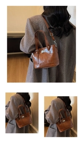 Detail view of brown leather bucket bag featuring metallic twist lock and double handles