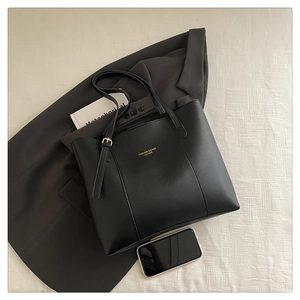 Detailed view of black leather tote bag with gold lettering and sleek metal buckle