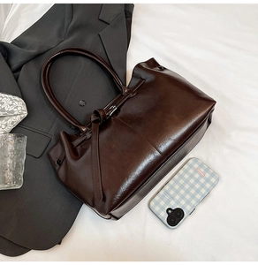 Detail of dark brown matte faux leather tote bag with elegant ribbon buckle design